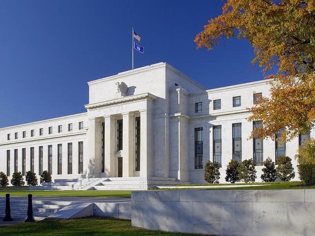 Federal Reserve building in Washington D.C. with columns and American flag.