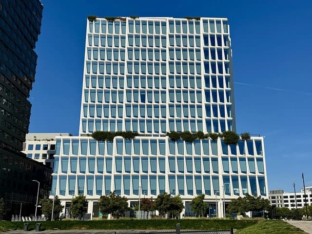 Visa headquarters building, a modern white skyscraper with many windows, against a blue sky.