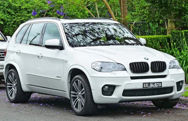 A white 2010-2011 BMW X5 xDrive35i wagon parked on a street.