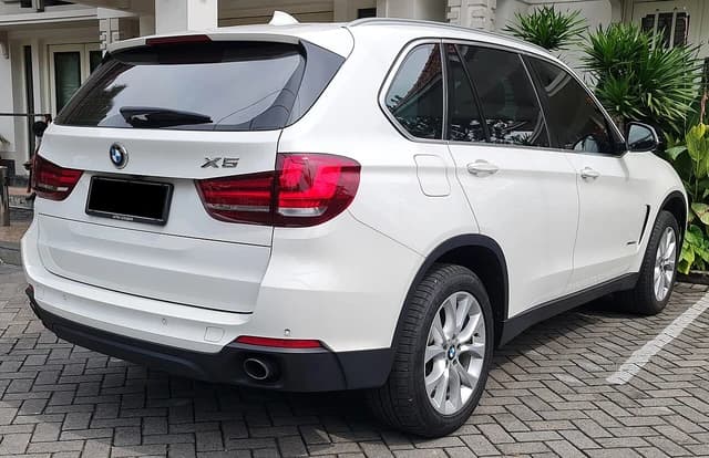Rear view of a white 2018 BMW X5 SUV parked outside a building.