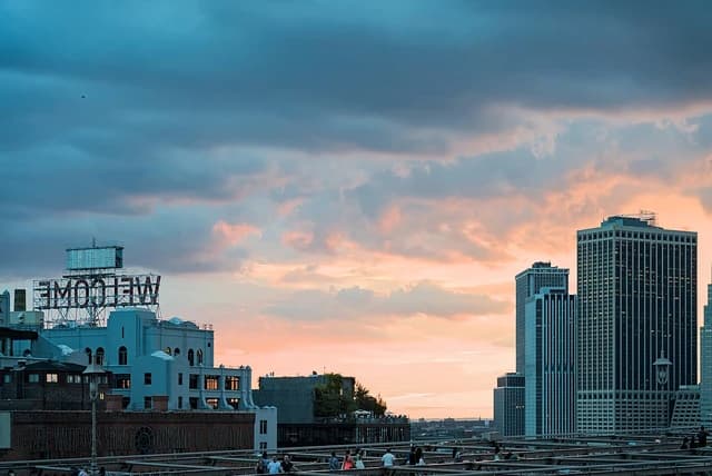 Sunset sky over buildings in Brooklyn with Manhattan's Financial District in the distance.