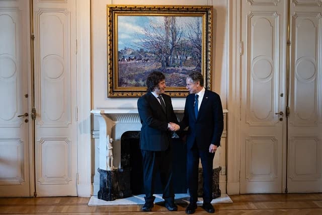 Argentine President Javier Milei shakes hands with Secretary of State Antony Blinken indoors.