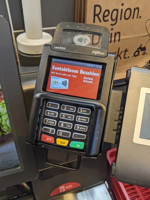 Close-up of a payment terminal at a self-checkout, displaying a 'contactless payment' screen.