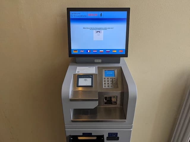 Payment terminal at the Berlin immigration office with a screen showing German text.