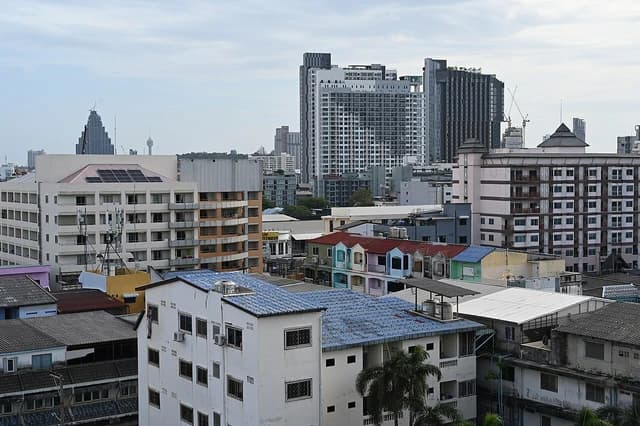 Pattaya skyline with residential rooftops in the foreground and modern high-rise buildings in the background.
