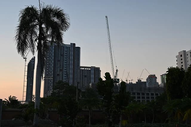 High-rise buildings and construction cranes silhouette the horizon at dusk in Pattaya, Thailand.
