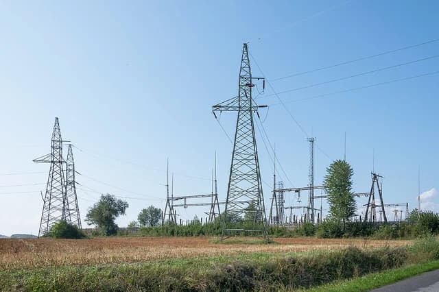 Electrical transmission towers and substation in Mszańcu, Poland, seen from a distance.
