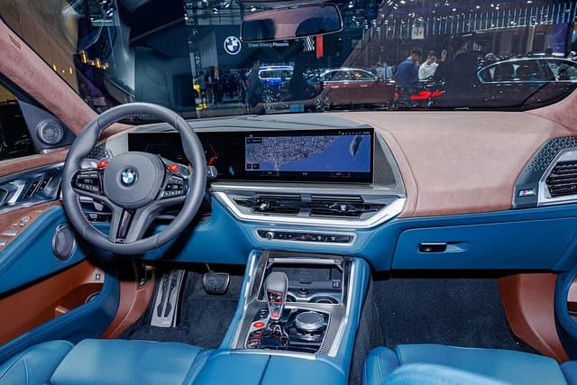 Interior of a BMW XM (G09) car, showing the steering wheel, dashboard, and central console.