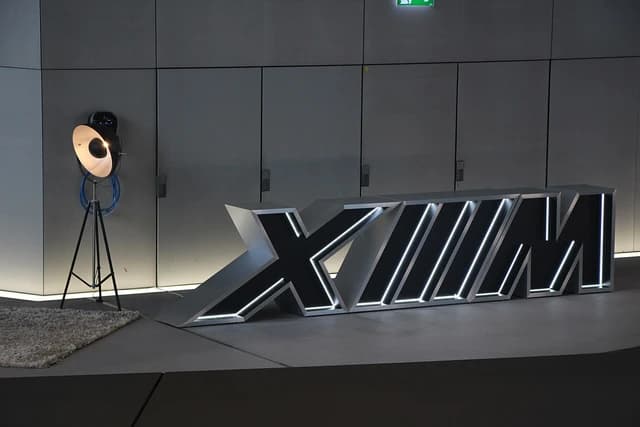 Large illuminated 'XM' letters on a display platform at an event.