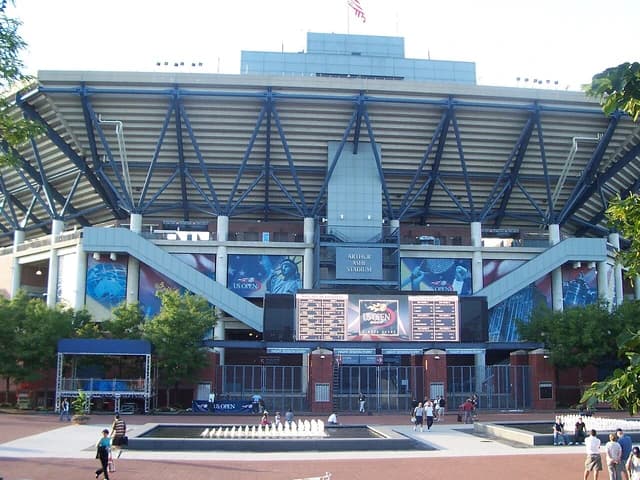 Exterior view of Arthur Ashe Stadium, showing its facade and surrounding plaza.