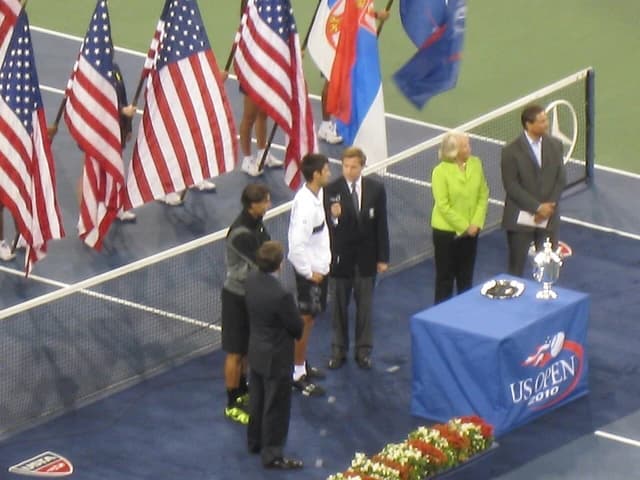 Tennis officials and athletes stand on court during trophy presentation at US Open.
