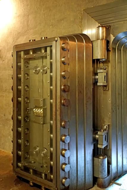 Massive, intricate Bank of Canada vault door, partially open, showing complex locking mechanism.