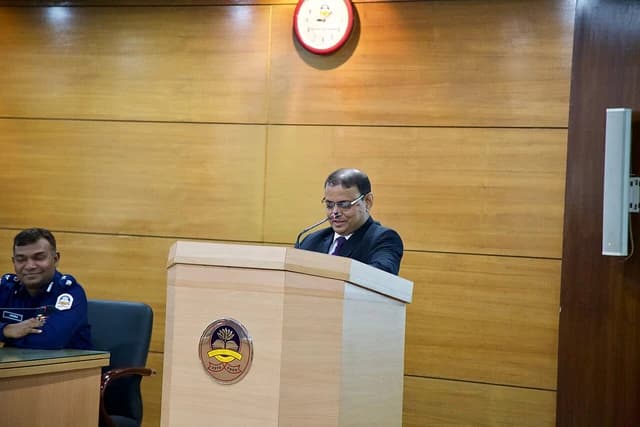 Man in suit speaking at a wooden podium at a financial investigations workshop.