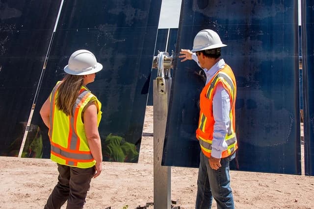 Erica Stewart and colleague examining solar panels outdoors.