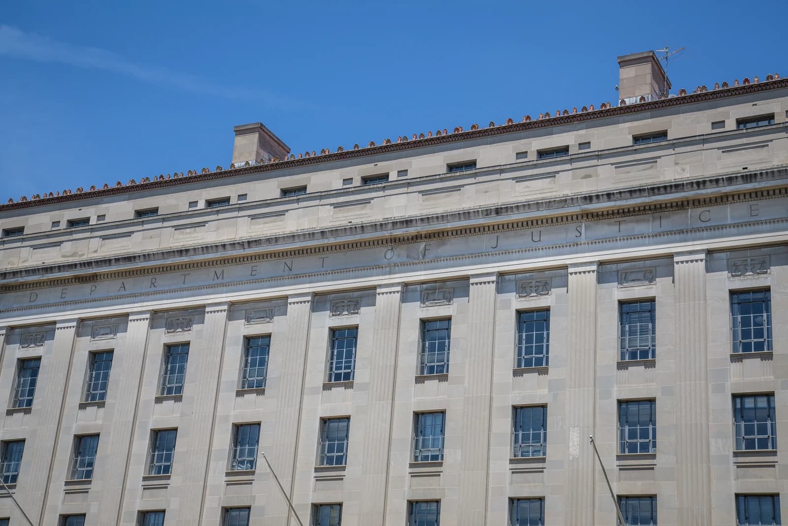 Exterior of the Department of Justice building in Washington, D.C. with clear blue sky.
