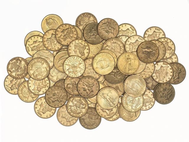 A scattered pile of gold double eagle coins from various years.