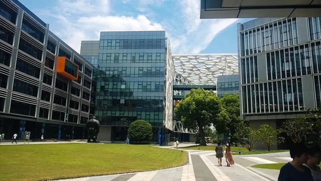 Alibaba Binjiang Park headquarters with modern buildings, green lawns, and people walking.