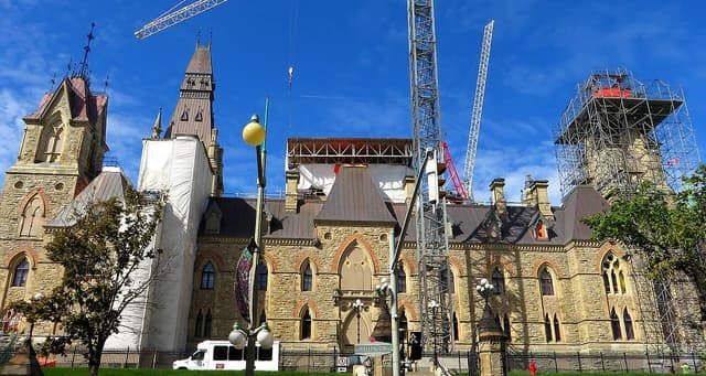 Parliament Hill buildings in Ottawa, Canada, under construction on a sunny day.