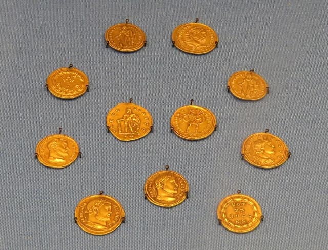Ancient Roman gold coins from the Beaurains hoard, displayed in rows on a blue background.