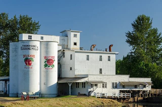 Thompson's Flour Mills building with large white silos in Shedd, Oregon.