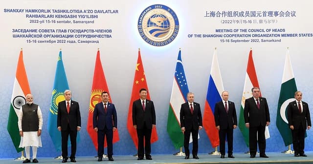 Heads of state and government from various nations stand in a line during a conference.