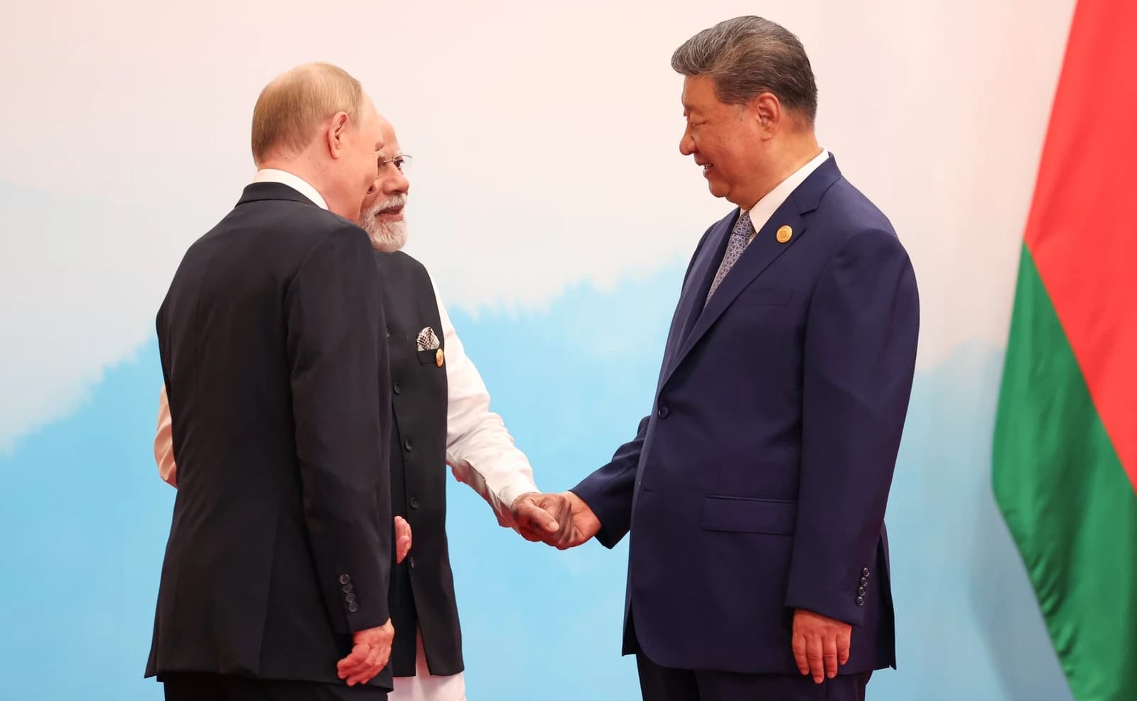 Vladimir Putin, Narendra Modi, and Xi Jinping shaking hands at a summit.