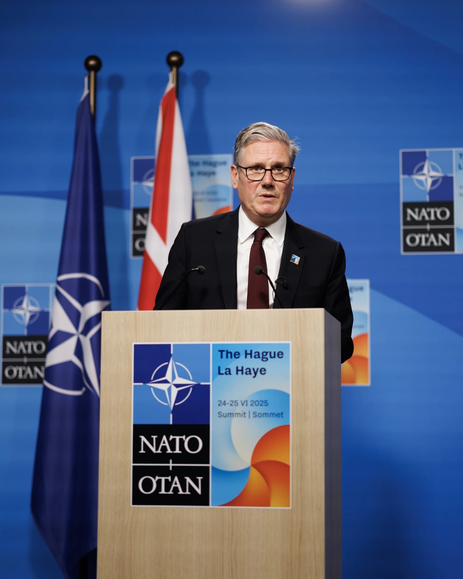 Keir Starmer, Leader of the Labour Party, speaking at a podium with NATO logos.