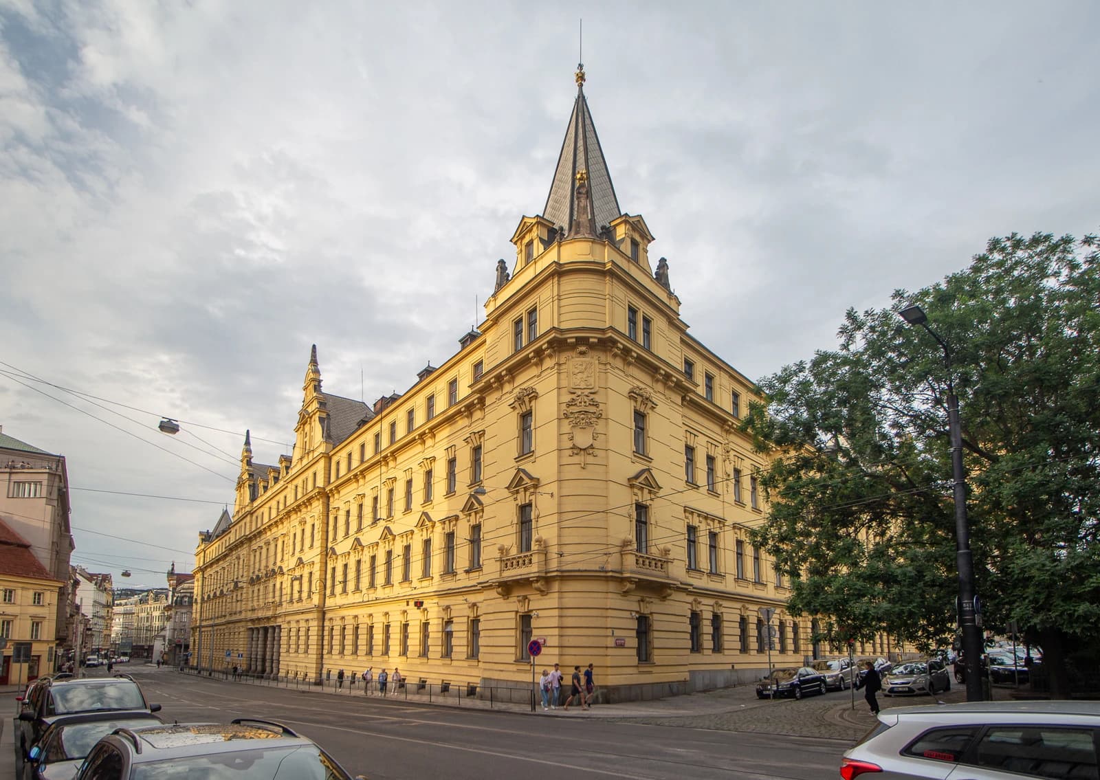 Exterior view of the Municipal Court in Prague, a yellow building with a prominent corner spire.