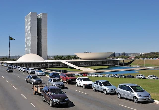 Brasília National Congress Buildings with two towers and two domes, a road, and cars.