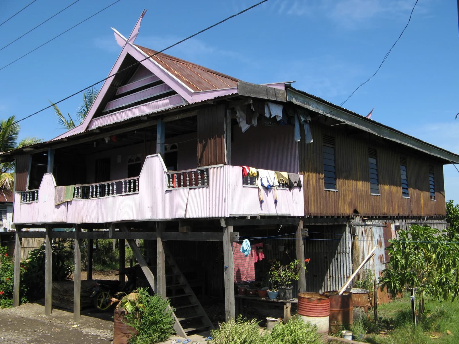 A house with a corrugated iron roof and wooden walls, built on stilts in Macassar.
