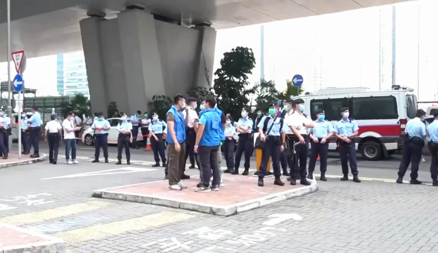 Police officers and other individuals stand outside the West Kowloon Law Courts Building in Hong Kong.