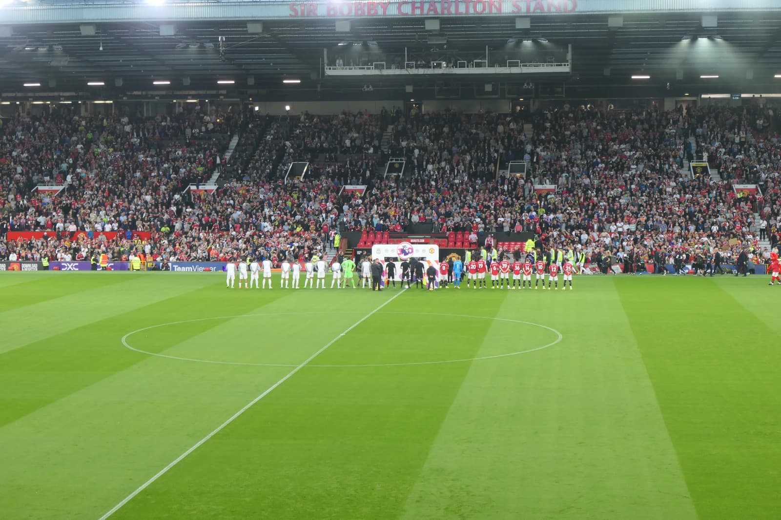 Manchester United and Liverpool players line up on the pitch before a match.
