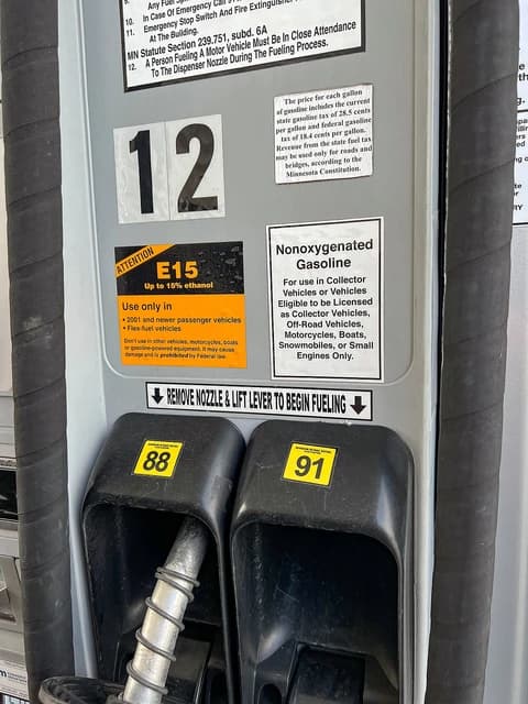 Close-up of gas pump nozzles at a station, labeled with 88 and 91 octane ratings.