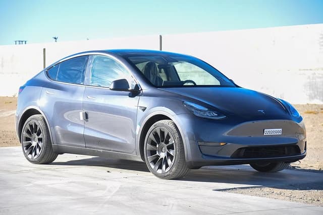 A gray 2020 Tesla Model Y parked outdoors with a testing label on the front.
