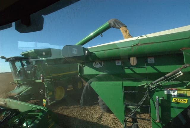 John Deere combine harvester filling an auger wagon with soybeans.