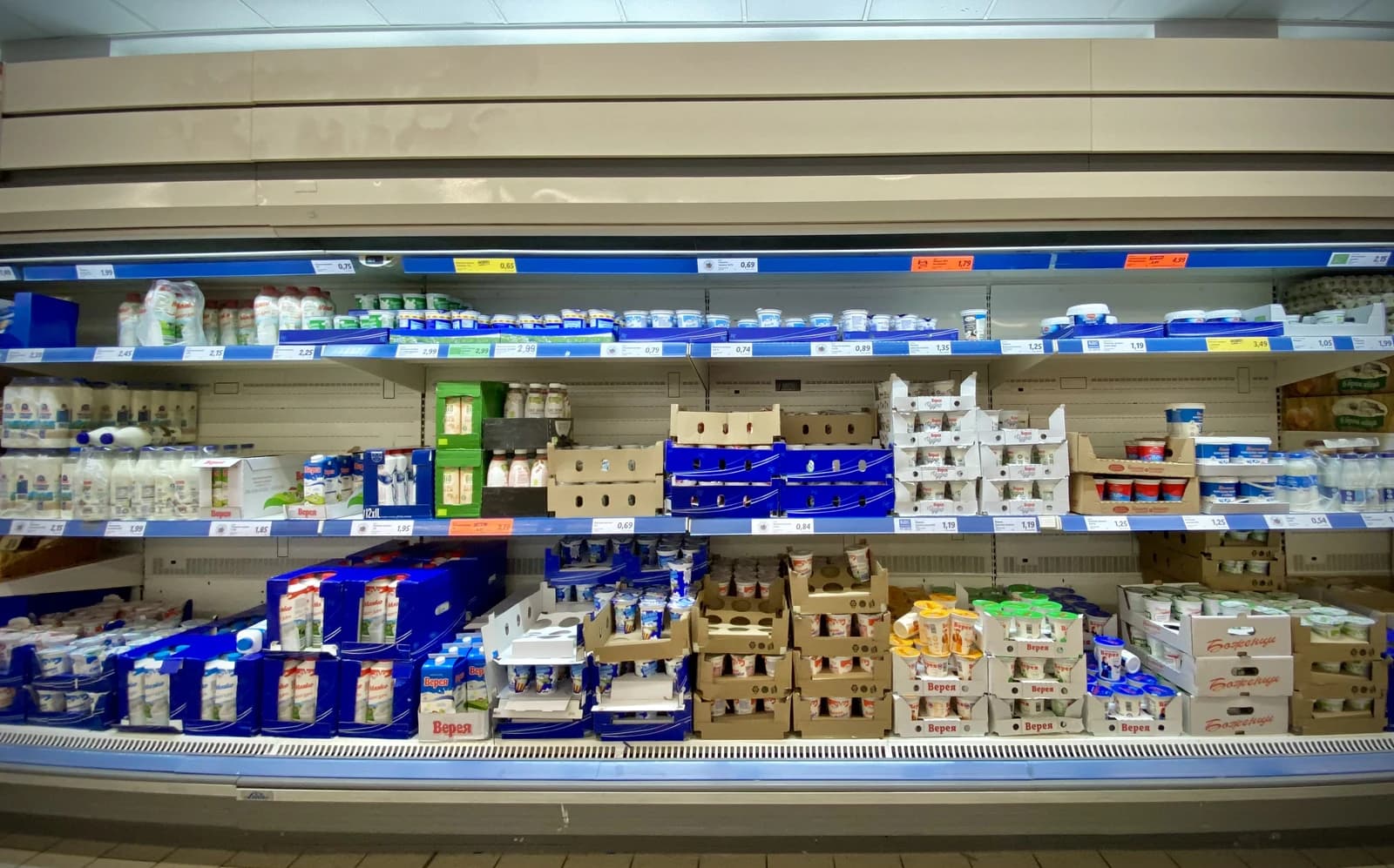 A refrigerated aisle in a supermarket filled with various yogurt and dairy products.