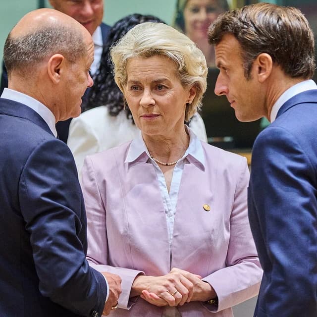 Emmanuel Macron, Ursula von der Leyen, and Olaf Scholz stand together, engaged in conversation.