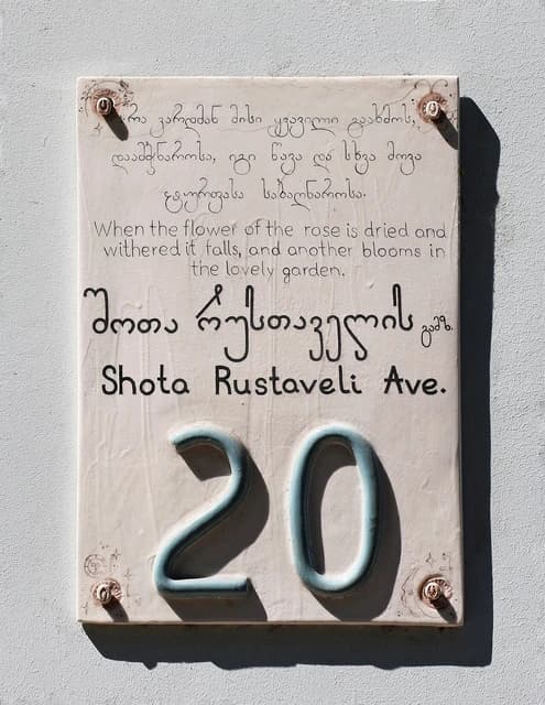 Decorative address plaque with Georgian and English text and the number 20.