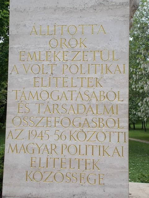 Close-up of a stone memorial with golden Hungarian inscription detailing communist victims.
