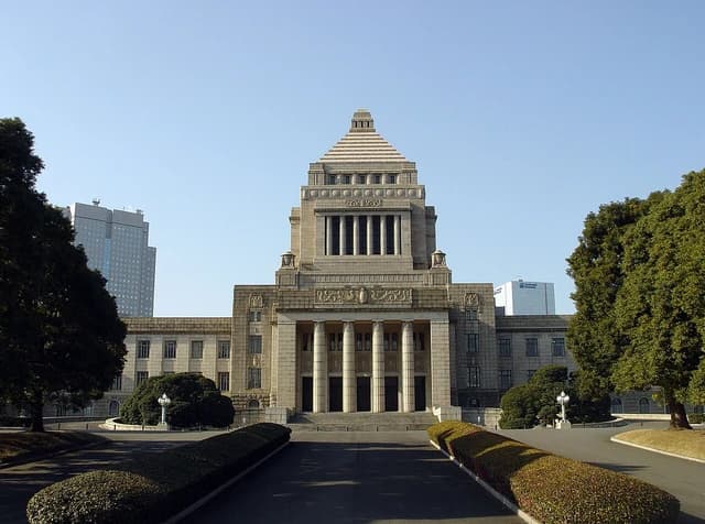Japan's National Diet Building, an imposing stone structure, viewed from an approach road.