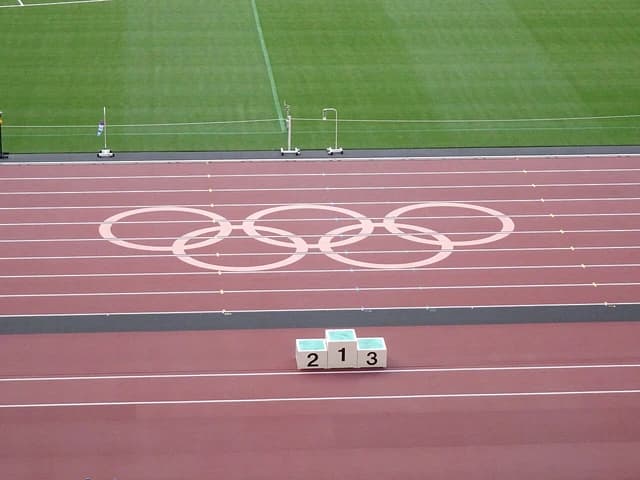 Olympic rings logo painted on a running track with a winners' podium at National Stadium, Tokyo.