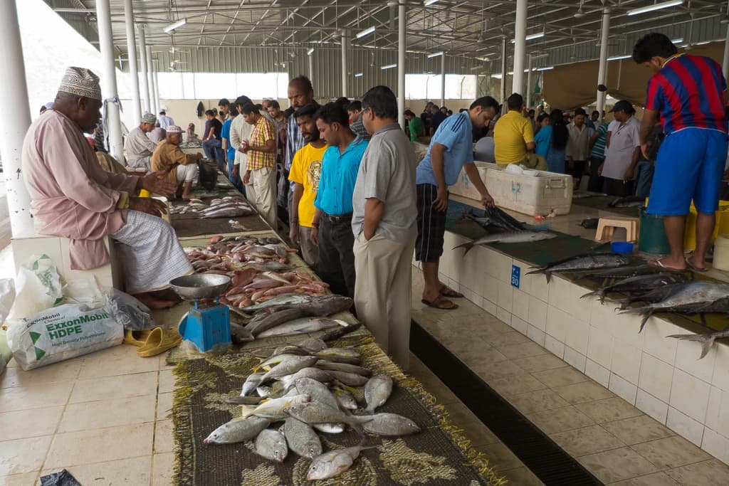 Men examine fish at a market stall in Mutrah, Muscat, Oman.