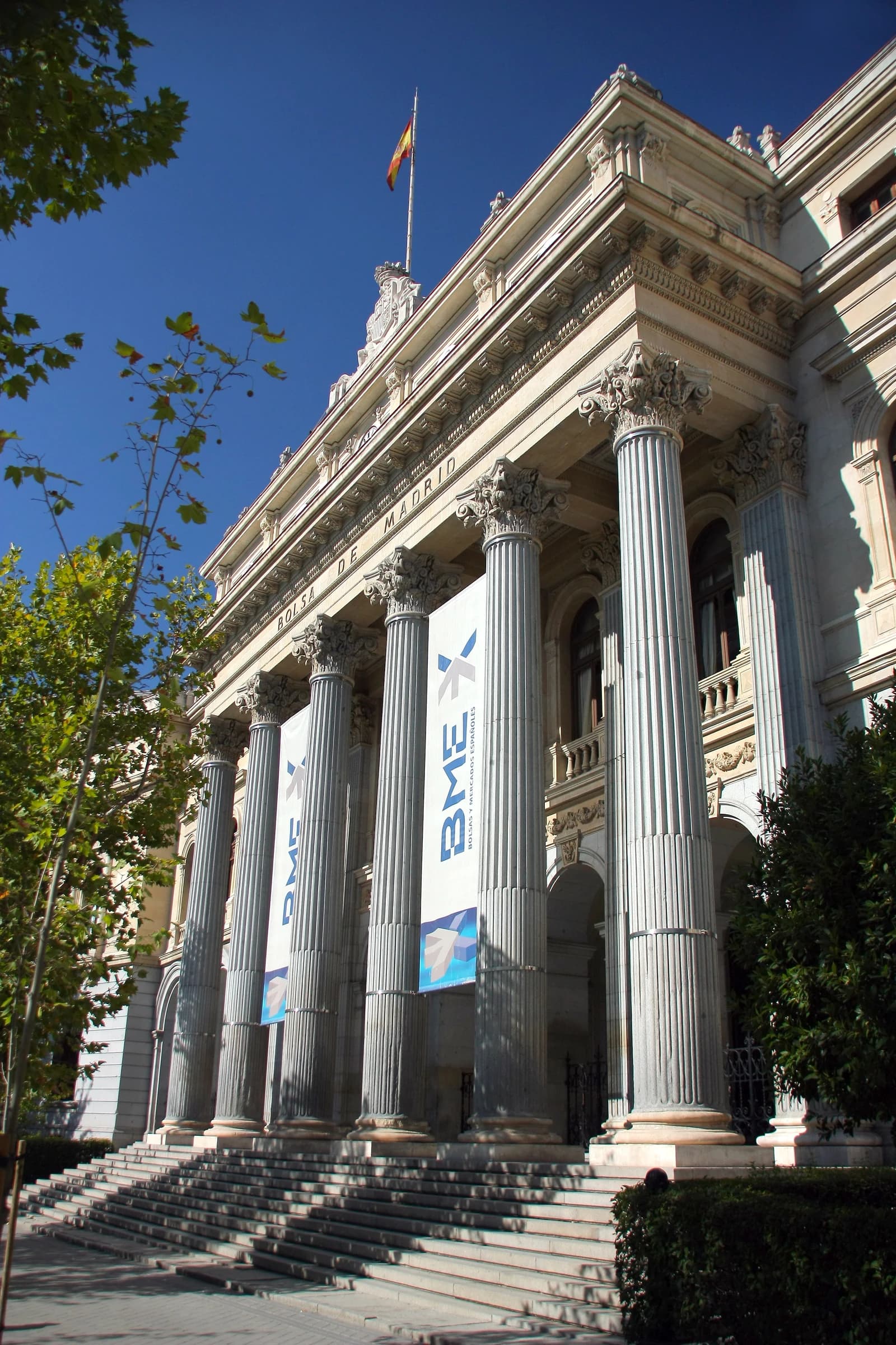 Exterior view of the ornate neoclassical Madrid Stock Exchange Building with large columns.