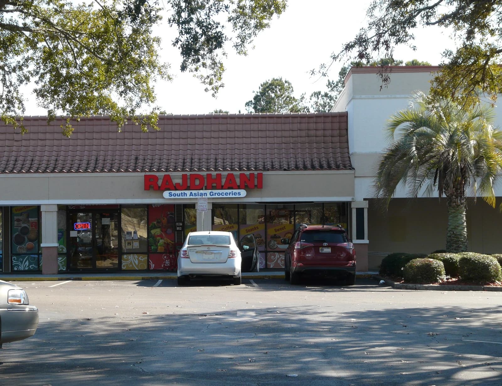 Exterior of Rajdhani South Asian Groceries store with parked cars in Tallahassee, Florida.