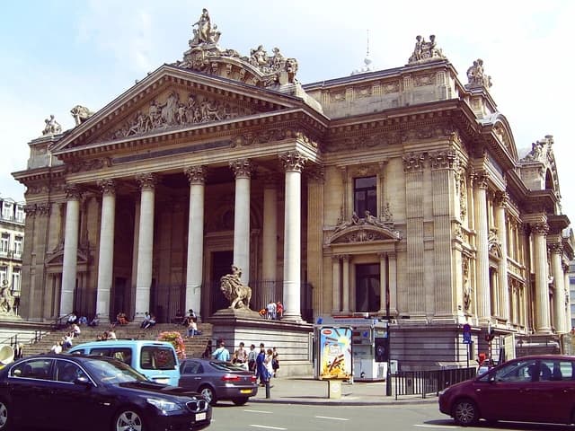 Grand stone building with classical columns and ornate sculptures at the Brussels Stock Exchange.