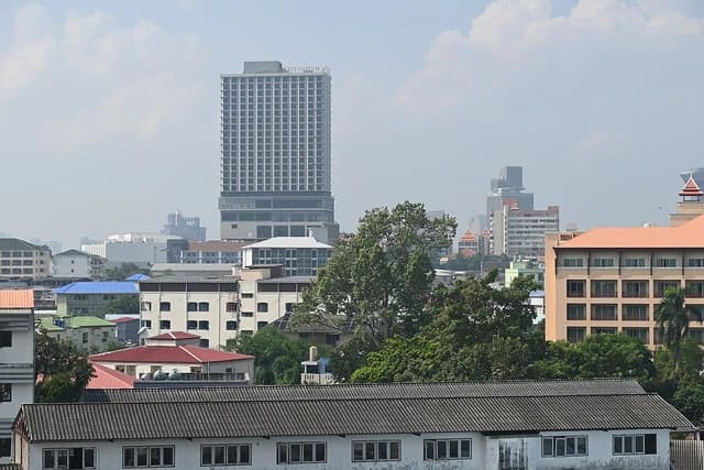 City skyline with a mix of buildings, trees, and a tall modern tower.