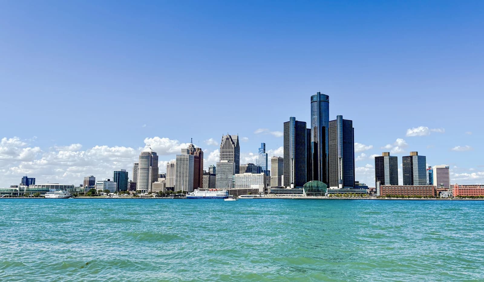Detroit skyline from Windsor with blue sky and Detroit River in the foreground.
