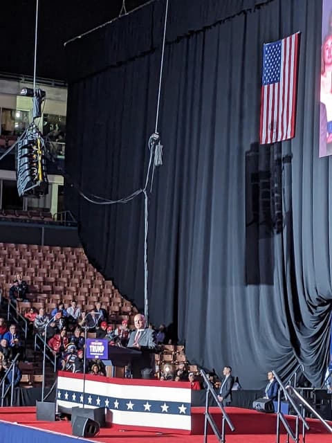 Donald Trump, former President, speaking at a podium inside an arena.