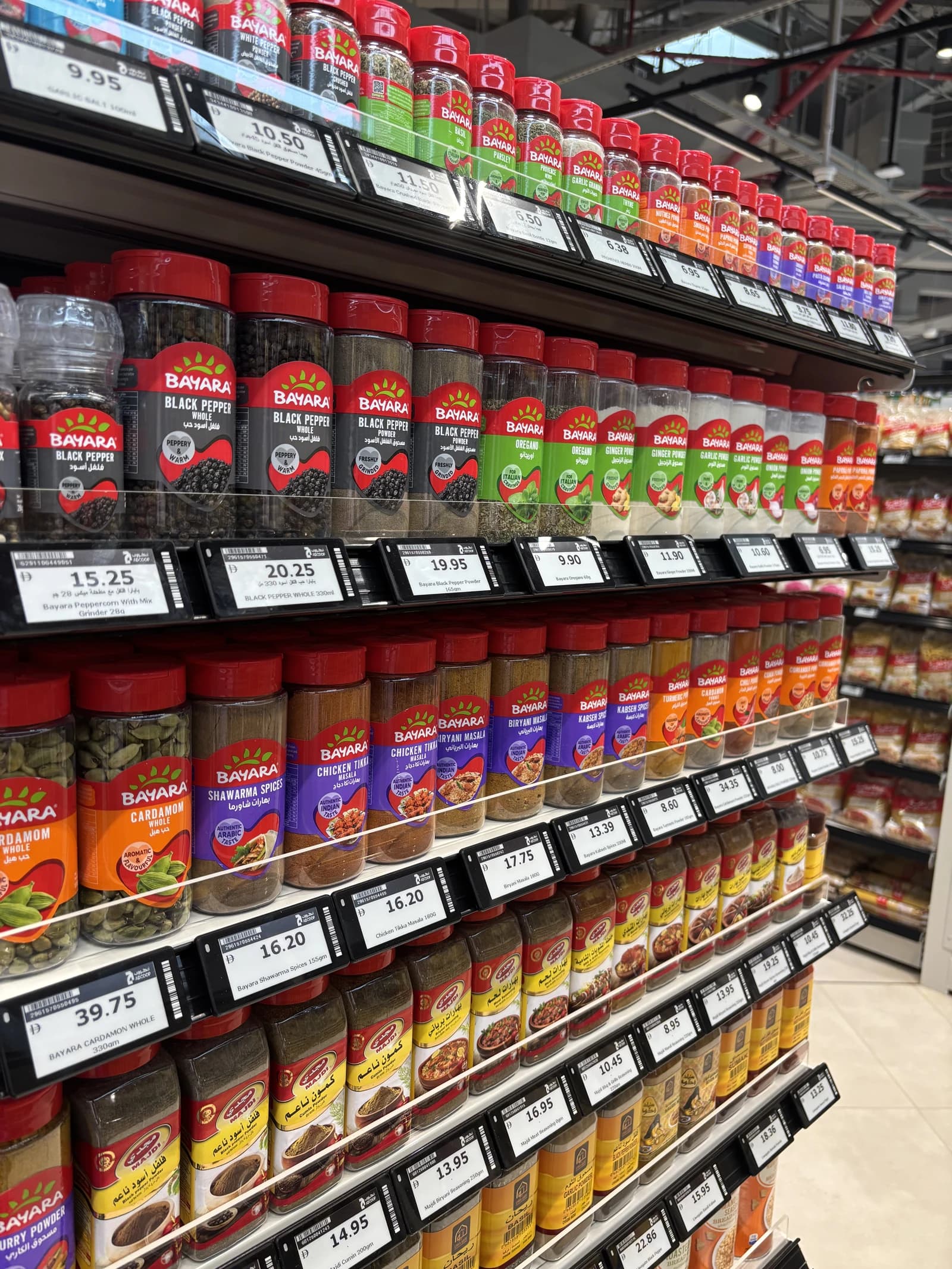 Electronic shelf labels showing prices on shelves of spice jars in a supermarket.