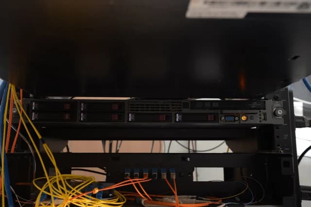 Server rack containing hard drives and various network cables in a data center.